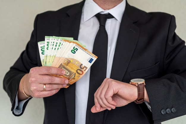 Man in suit holding euro banknotes at business center Concept of payment or giving cash financial