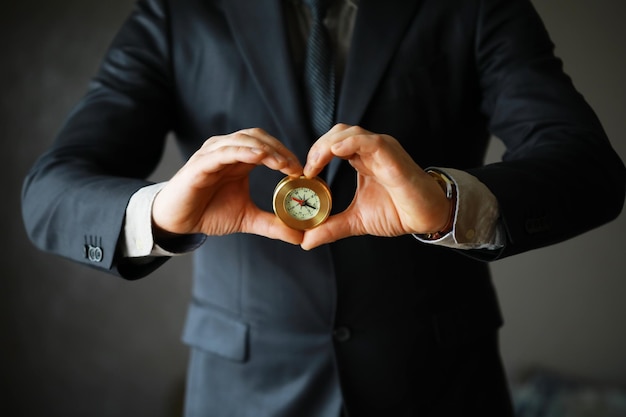 Man in suit holding golden compass on gray background