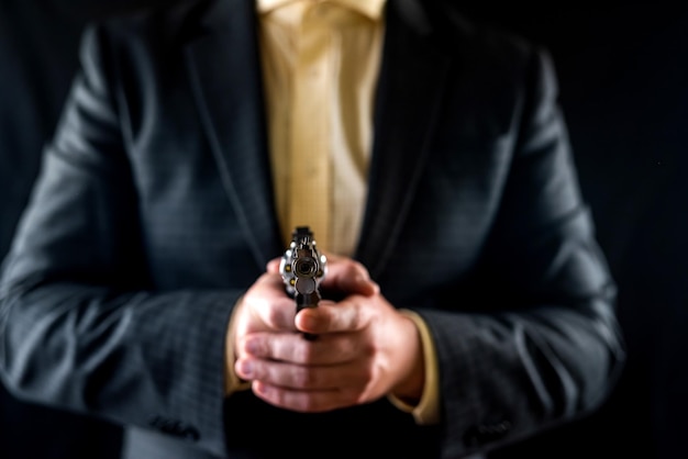 Man in a suit holding a gun as a secret agent isolated on a black background