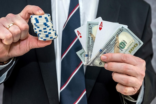 Мужчина в костюме держит игральную карту с игрой в покер с долларовыми купюрами