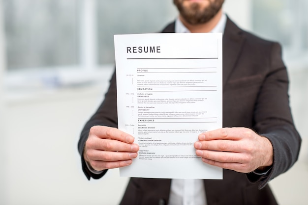 Photo man in the suit holding resume for job hiring. close-up view focused on the paper