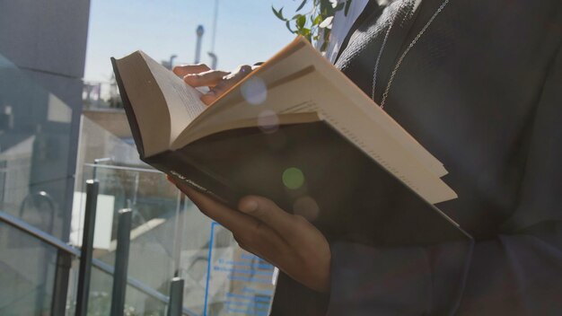 A man in a suit holds a book with the title'the book'on the cover.