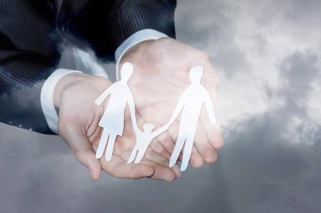 A man in a suit holds a paper cutout of a family.