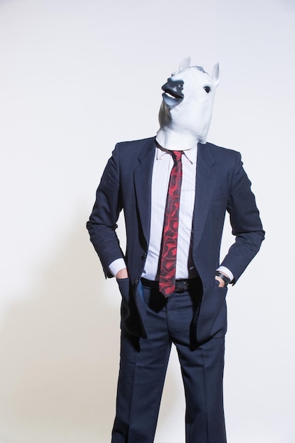 A man in a suit and a horse mask on a light background Conceptual business background