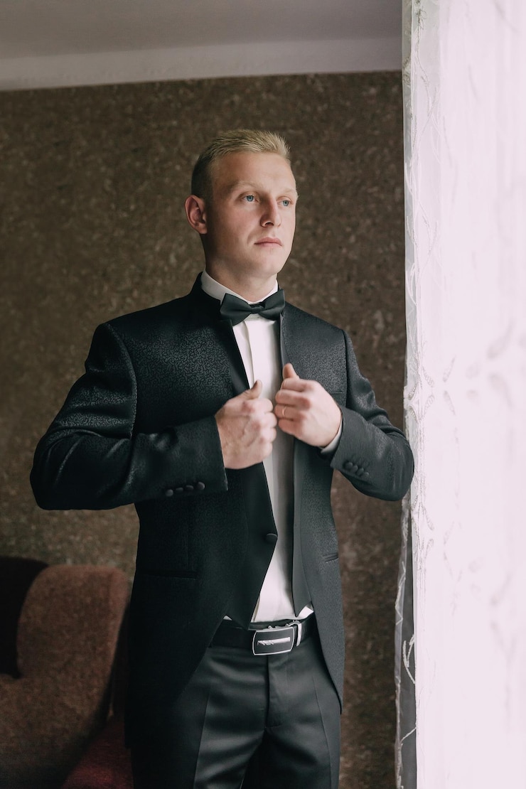 Photo a man in a suit is getting ready to tie his bow tie