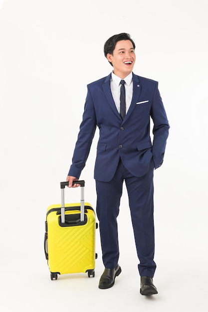 A man in a suit is holding a yellow suitcase and smiling