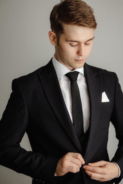 A man in a suit is looking down at his watch.