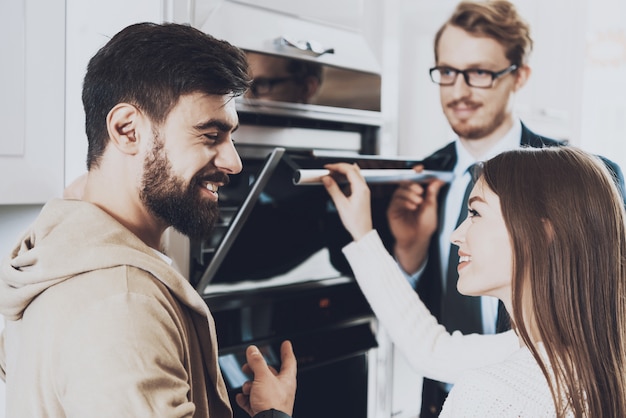 Man in suit is showing built-in stove to couple