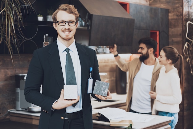 Man in suit is showing different materials for camera