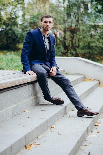 A man in a suit is sitting on a bench in the park