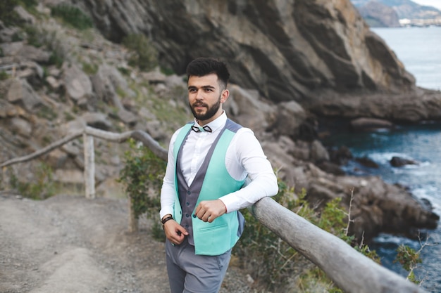 Man in suit in nature. Portrait of the groom. Smiles.