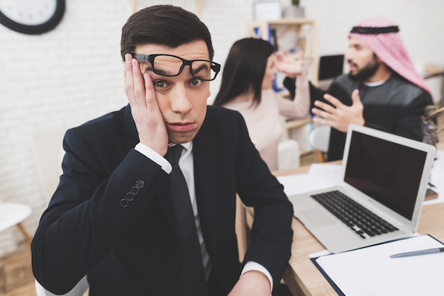 Man in suit in office with arab husband and wife.