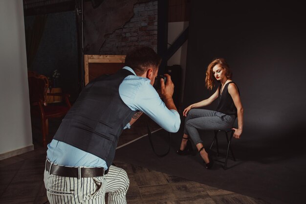 the man in a suit photographing a beautiful woman on a dark background in the photostudio