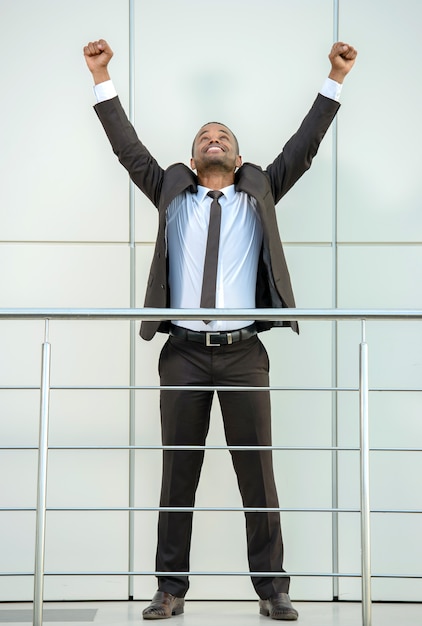 Man in suit raised his hands up and smiles.