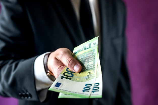 Man in a suit and shirt counts the euro bills he received for the work done in the office