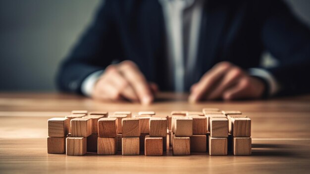 A man in a suit sits at a table with wooden cubes.