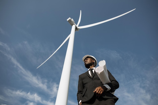 Man in suit standing among windmills with blueprints