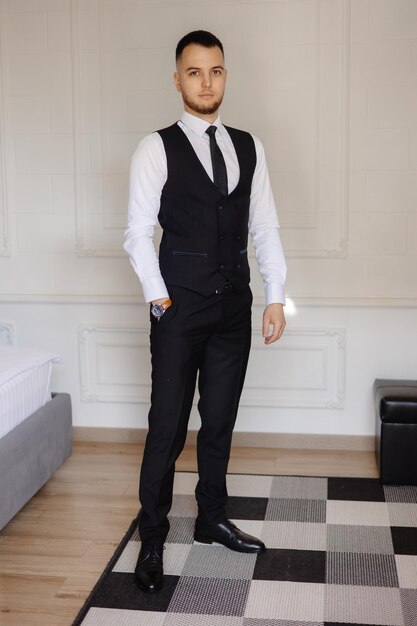 a man in a suit stands in front of a bed