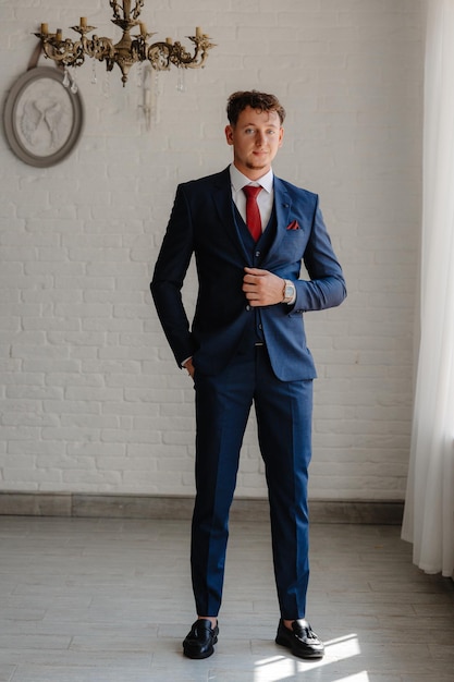 a man in a suit stands in front of a brick wall