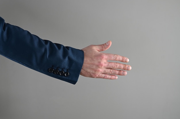 A man in a suit stretches out his hand