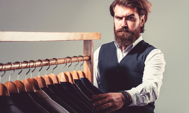 Man suit tailor in his workshop Male suits hanging in a row Tailor tailoring Stylish men's suit Handsome bearded fashion man in classical costume suit