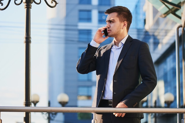 Man in suit talking on mobile phone against the building with a glass facade