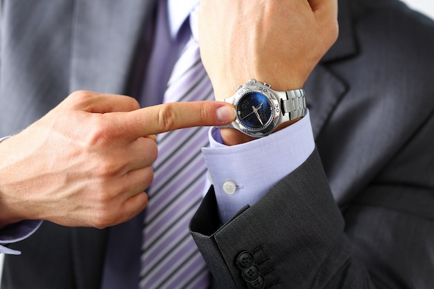 Man in suit and tie check out time at silver wristwatch