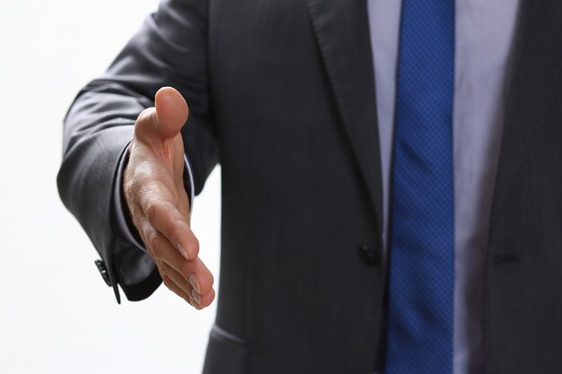 Man in suit and tie give hand as hello in office