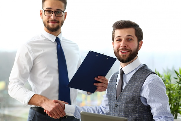 Man in suit and tie give hand as hello in office