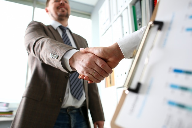 Man in suit and tie give hand as hello in office