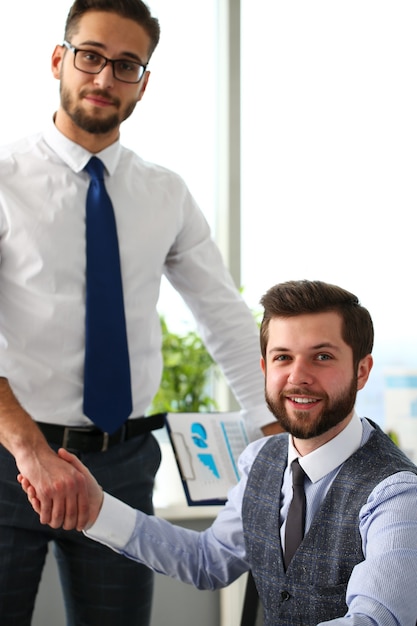 Man in suit and tie give hand as hello in office