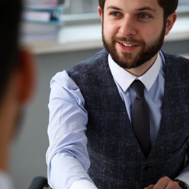 Man in suit and tie give hand as hello in office