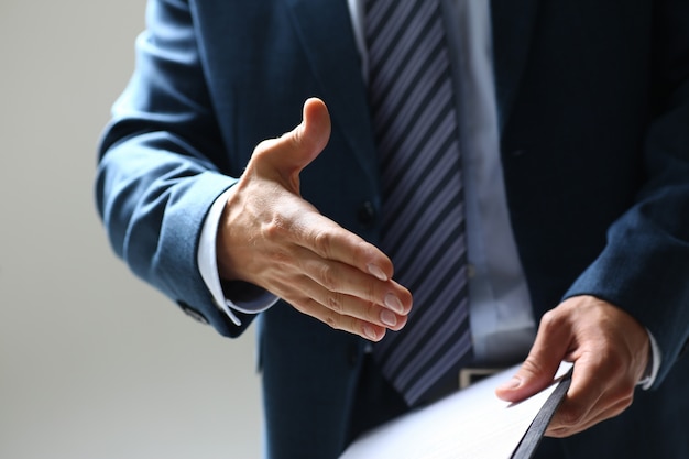 Man in suit and tie give hand as hello