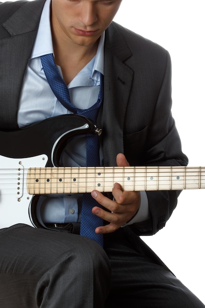 Man in suit and tie playing electric guitar isolated on white