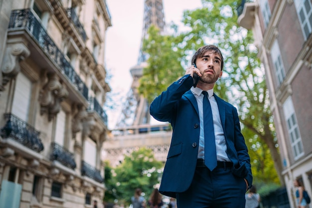 Man in a suit using her smartphone in Paris France European worker Street with Eiffel Tower view