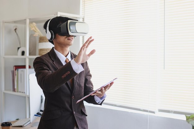 Man in suit using virtual reality glasses and headphones is gesturing hands as if touching something