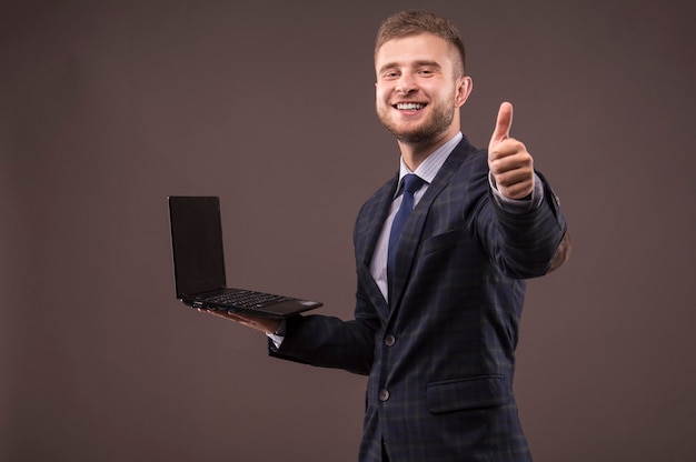 Man in suit with laptop in his hands shows OK sign