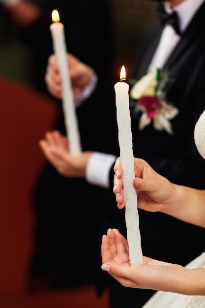 Foto un uomo in abito e una donna in abito da sposa tengono delle candele