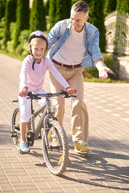 自転車に乗っている女の子を支える男