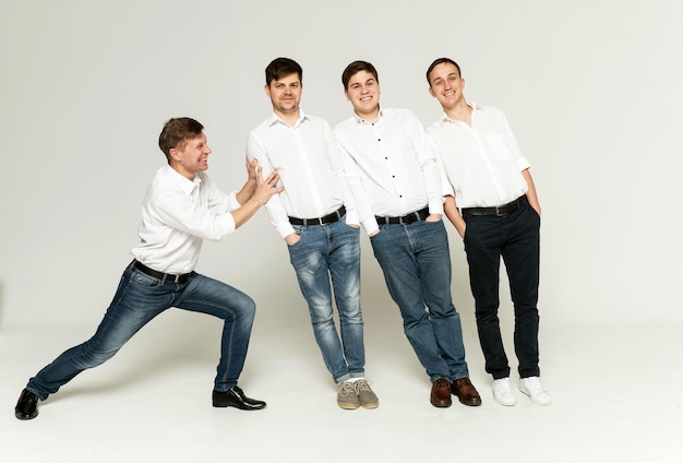 A man supports guys on a white background. four men have fun in the studio on a white background.father with three sons playing.