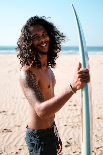Человек-серфер сидит за доской для серфинга на песчаном пляже
