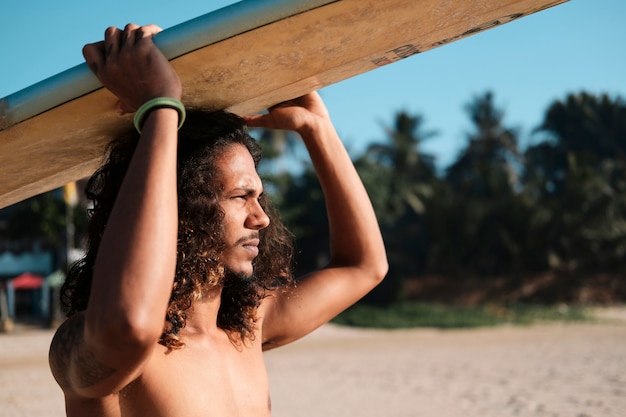 Man surfer zit op surfplank op zandstrand