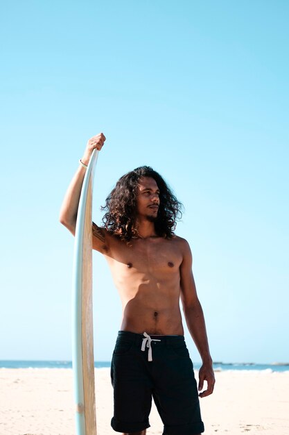 Man surfer zittend op surfplank op zand strand