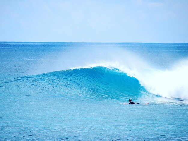 写真 空に逆らって海でサーフィンをする男