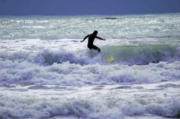 写真 空に逆らって海でサーフィンをする男