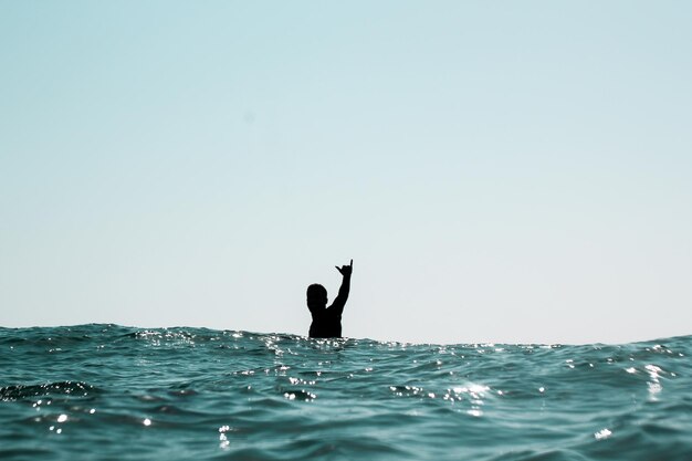 晴れた空の下で海をサーフィンしている男