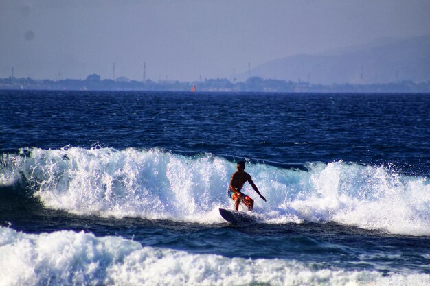 Man surfing in sea against clear sky