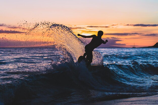 Foto uomo che fa surf in mare contro il cielo durante il tramonto