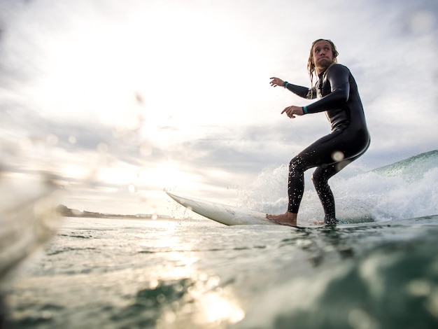 man surfing in sea against sky