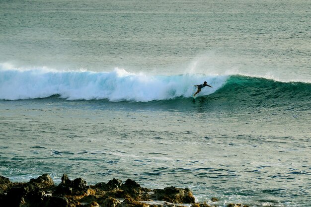 Foto uomo che fa surf sulla tavola in mare